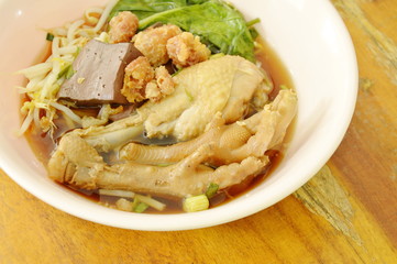 boiled chicken leg and feet with bean sprout in herb brown soup on bowl