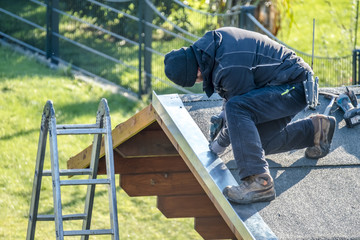 Roofer worker using battery-powered screw gun