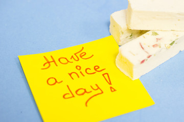 Pieces of vanilla fudge with fruit and Have a Nice Day yellow sticker note on a blue background