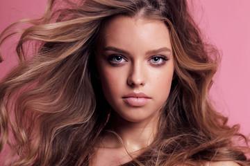 Naklejka premium beautiful young girl with blond hair in cozy clothes posing in studio
