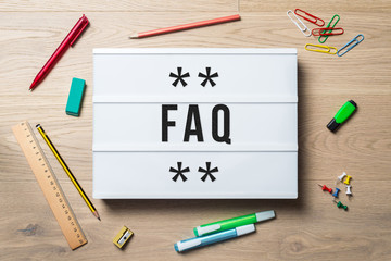 FAQ written on lightbox lying on desk as flatlay