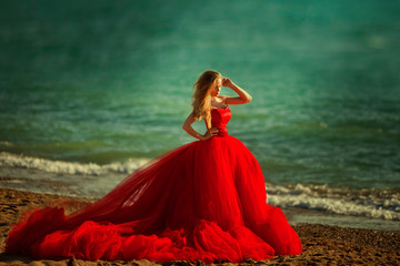 Fototapeta na wymiar Beautiful girl by the sea. A woman in a red dress on the beach.