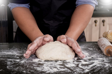 Woman's hands knead dough with flour, eggs and ingredients. at kitchen.
