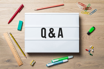 Q & A written on lightbox in office as flatlay