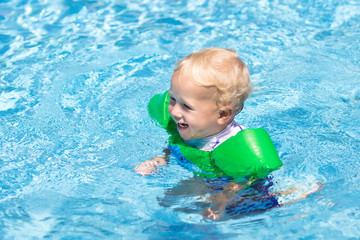 Fototapeta na wymiar Baby with inflatable armbands in swimming pool.