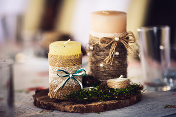 Candles wrapped in burlap and decorated with a bow-knot, lace and moss