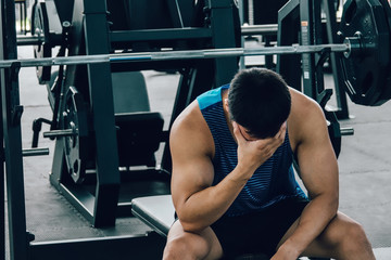Tired man taking a workout rest. Male athlete suffering a headache or dizziness. Unmotivation in sport and tiredness concept. 