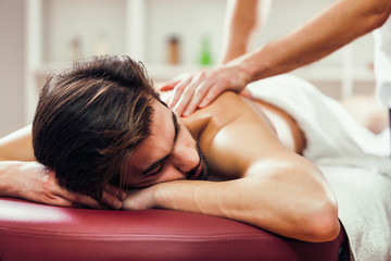 Obraz na płótnie Canvas Young man is enjoying massage on spa treatment. 