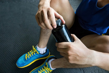Sport man opening the bottle of pills in the gym