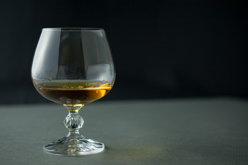glass of whiskey or cognac or alcohol drink, alcoholism and alcohol abuse concept, defocused, selective focus, close up, gray table, dark background