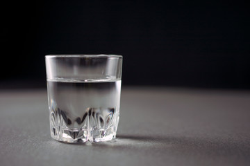 glass of vodka or alcohol drink, alcoholism and alcohol abuse concept, defocused, selective focus, close up, gray table, dark background