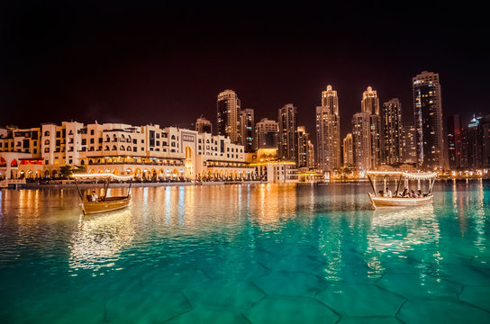 Singing fountains in Dubai. Dubai promenade singing fountains on the background of architecture. Traditional arabic boat Abra