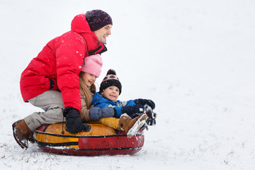 Fototapeta na wymiar Image of happy father, daughter and son on tubing in winter park