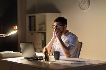 tired businessman with laptop at night office