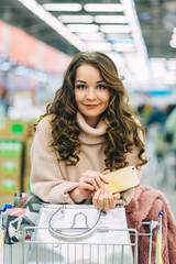 Portrait of young beautiful woman in supermatket holding a phone