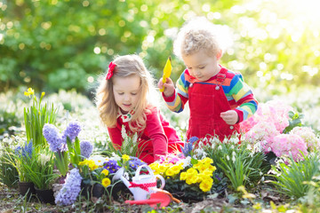 Kids plant and water flowers in spring garden