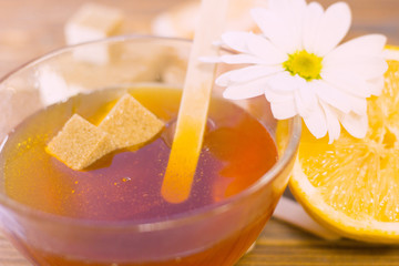 Spa procedures concept. Brown sugar cubes in a bowl of honey and lemon, natural dark wooden background, top view