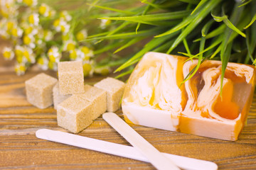 A set of spa essentials with fruit soap, brown sugar and camomile on a natural dark wooden background