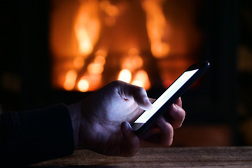 A man texting a message where a present is, with a fireplace in the background