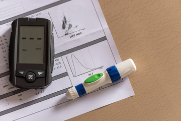 Blood level hemogram report with blood glucose meter on a wooden background.