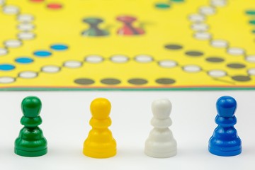 Board game with different colored game pawns on it. Ludo or Sorry board game play figures isolated on white background