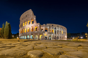 Fototapeta premium Nocny widok na Koloseum w Rzymie, Włochy. Rzymska architektura i punkt orientacyjny. Rzymskie Koloseum to jedna z głównych atrakcji Rzymu i Włoch