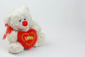 White Teddy bear holding red heart with text LOVE, isolated on white background, Valentine's Day