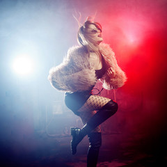 Fashionable young woman in a fluffy pink coat, neon light. Portrait of a beautiful trendy girl