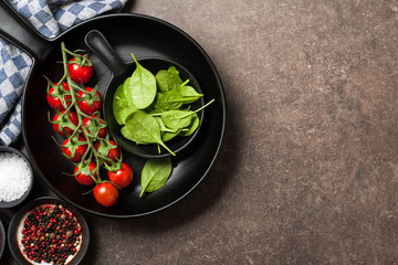 Cooking table with fresh tomatoes, spinach leaves and spices