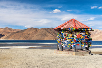 Red pavilion in Mountains and Pangong tso (Lake). It is huge and highest lake in Ladakh and blue sky in background, it extends from India to Tibet. Leh, Ladakh, Jammu and Kashmir, India