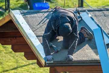 Roofer worker using battery-powered screw gun