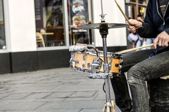 young white man/busker/drummer drumming in the street