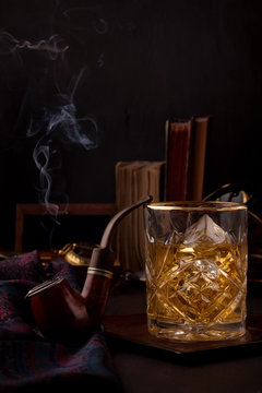 A glass of whisky and smoking pipe