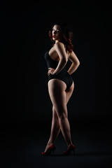 Fototapeta na wymiar Beautiful sexy woman in bodysuit posing on black background, low key studio shot