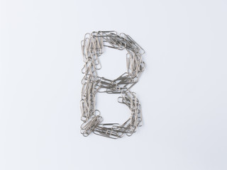 Letter B displayed with paperclips on white background