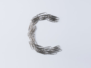 Letter C displayed with paperclips on white background