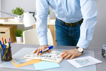 Photographer writes in diary and standing at the desk