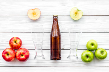 Apple cider. Low-alcoholic beveradge in dark bottle near beer glasses and fresh apples on white wooden background top view