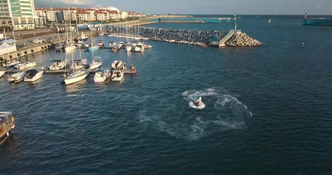Man on a jet-ski does stunts flip in the bay. Shooting from the air front