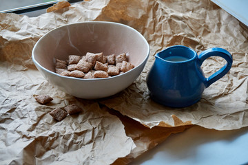 Dry breakfast is poured with milk into plates from a jug for milk