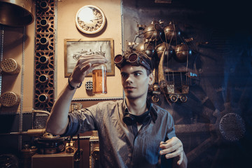 Portrait of a young mad scientist dressed in steampunk style and glasses in his fantastic...