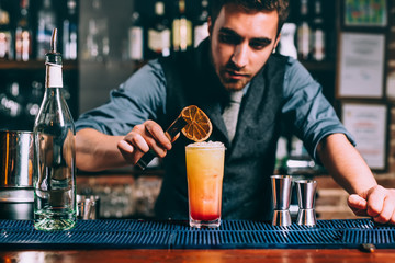 professional bartender preparing summer cocktail with glass and orange
