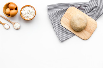 Ball of fresh raw dough near ingedients and cookware on white background top view copy space