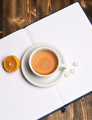 Hot beverage with sugar cubes placed on open book