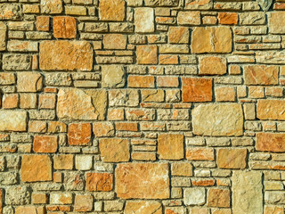 Wall of orange and beige stones. Stone wall.
