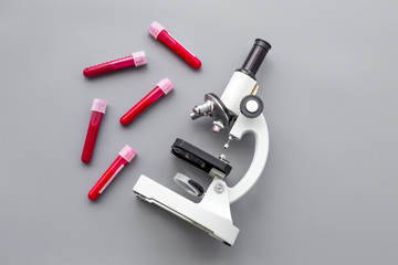 Do blood test in laboratory. Analysis. Blood samples in test tubes near microscope on grey background top view copy space