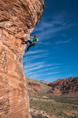 Man rock climbing red rock in desert