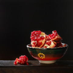 Purified pomegranate in a beautiful ceramic green cup on a  black background.