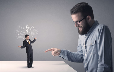Young businessman fighting with miniature businessman
