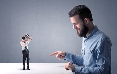 Young businessman fighting with miniature businessman
